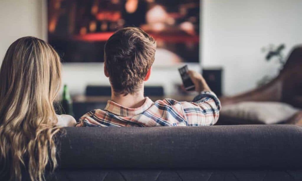 man and woman on a couch watching tv